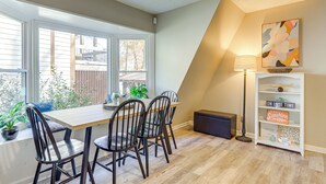 Een eethoek met een tafel, stoelen, een lamp en een boekenkast met decoratieve spullen.