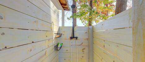 A wooden cabin with a small enclosed area, possibly a shower or storage space, with a ladder and a metal rack holding items.