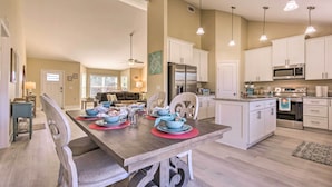 A spacious kitchen with white cabinets, a central island, and pendant lighting.