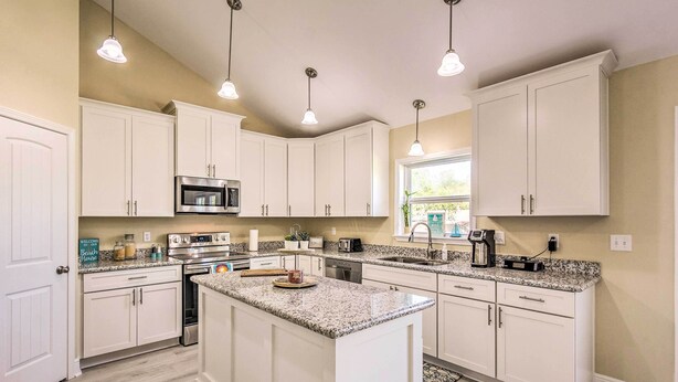 A kitchen with white cabinets, a granite countertop, and stainless steel appliances.