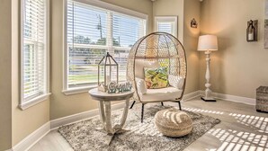 A cozy room with a wicker chair, a small table with a decorative item, and a lamp.