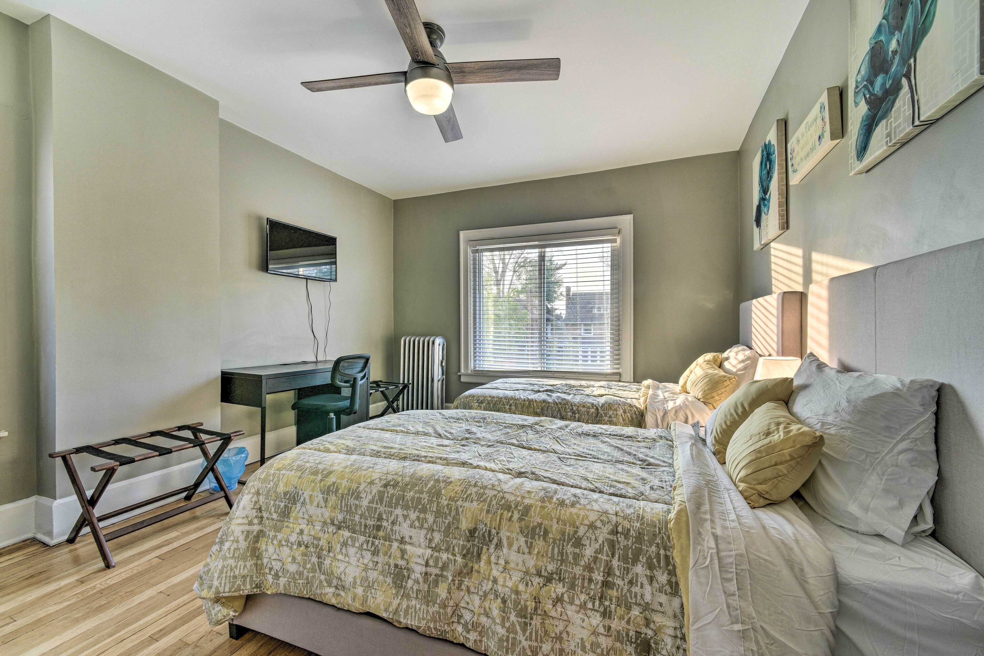 A bedroom with a bed, a desk, a chair, and a ceiling fan.