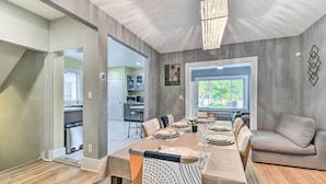 A dining area with a long table set for six, a sofa, and a chandelier. - Elegant Detroit Home w/ Yard ~ 5 Mi to Dtwn! (Detroit)