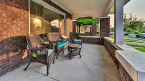 A covered patio area with wicker furniture and a brick wall. - Elegant Detroit Home w/ Yard ~ 5 Mi to Dtwn! (Detroit)