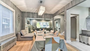 A modern dining area with a long table set for six, a sofa, and a kitchen area visible in the background. - Elegant Detroit Home w/ Yard ~ 5 Mi to Dtwn! (Detroit)