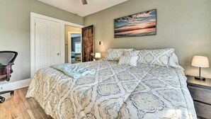 A bedroom with a bed, a ceiling fan, a nightstand with a lamp, a chair, and a door leading to another room. - Elegant Detroit Home w/ Yard ~ 5 Mi to Dtwn! (Detroit)