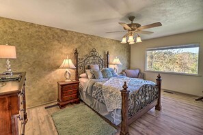 Classic bedroom with a large bed, bedside tables, and a ceiling fan, offering a view of the outdoors.