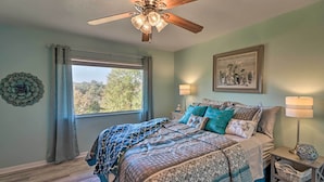 A bedroom with a bed, a ceiling fan, a window with curtains, a wall-mounted lamp, and a framed picture. - Large Home w/ Games: 4 Mi to Bull Shoals Lake! (Lakeview)