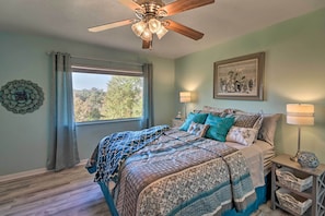 A bedroom with a bed, a ceiling fan, a window with curtains, a wall-mounted lamp, and a framed picture. - Large Home w/ Games: 4 Mi to Bull Shoals Lake! (Lakeview)