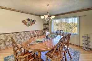 Enjoy meals in this dining room with a large table and six chairs, a chandelier, and a window with blinds.