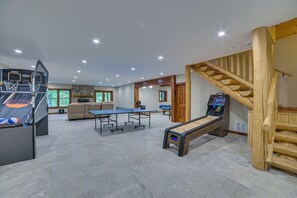 Un grand espace intérieur comprenant une table de ping-pong, un baby-foot et une table de billard.