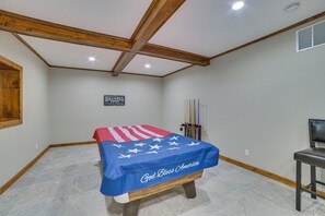 Quarto com mesa de bilhar, placa indicando sala de bilhar e toalha de mesa com tema de bandeira.