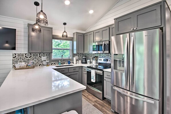 A modern kitchen with stainless steel appliances, a large island, and decorative pendant lighting.