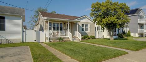 A row of single-story houses with front porches, a tree in the center, and a clear sky.