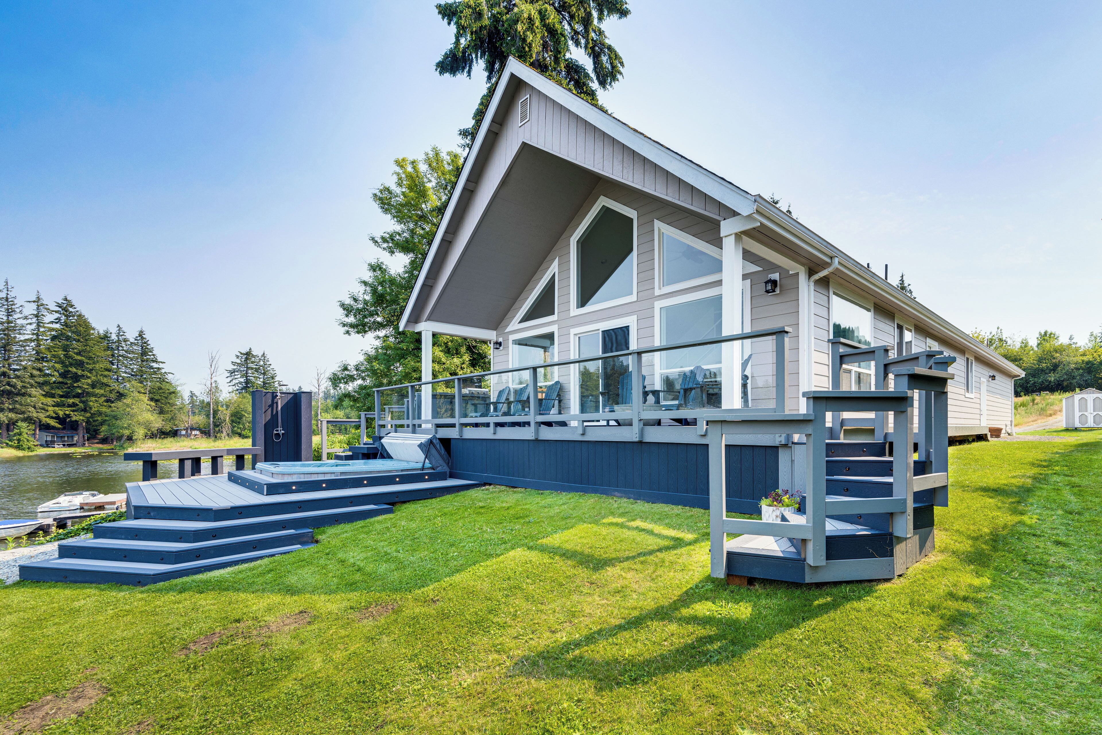 Een moderne woning met een ruim terras, een zwembad en uitzicht op een meer.