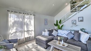 A modern living room with a sectional sofa, a coffee table, and a staircase.