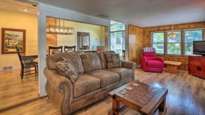 A spacious living room with a brown leather couch, a red armchair, and a wooden coffee table. - Pet-friendly Home w/ Views of Lake Delavan! (Delavan)
