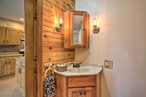 A wooden bathroom vanity with a mirror, two wall-mounted light fixtures, and a sink. - Pet-friendly Home w/ Views of Lake Delavan! (Delavan)
