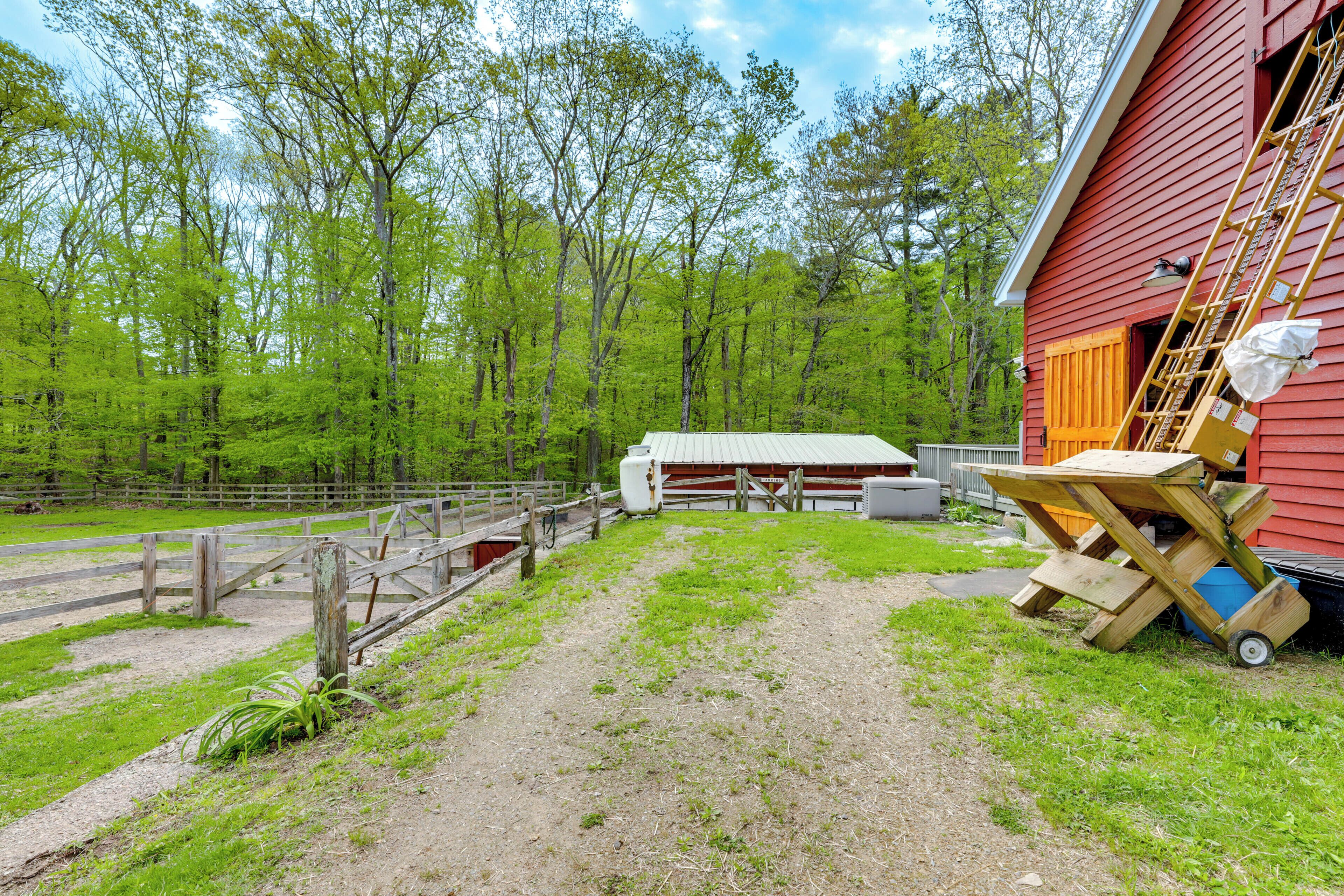Ein rotes Bauernhaus mit einer Holzleiter und einem Picknicktisch vor der Tür.