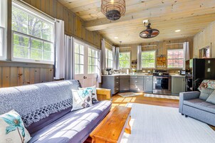 Un interior acogedor de cabaña con sofá, banco, mesa de comedor y zona de cocina.