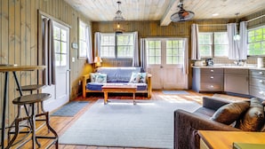 A cozy cabin interior with a wooden ceiling, a sofa, a dining table, and a kitchen area. - Killingly Barnyard Studio in Wine Country! (Dayville)