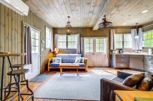 Un interior de cabaña acogedor, con techo de madera, un sofá, una mesa de comedor y una zona de cocina.