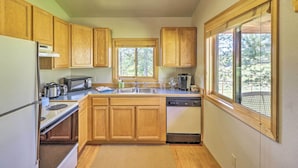 Una cocina con armarios de madera, un refrigerador, un microondas, una estufa, un lavabo y un lavavajillas.