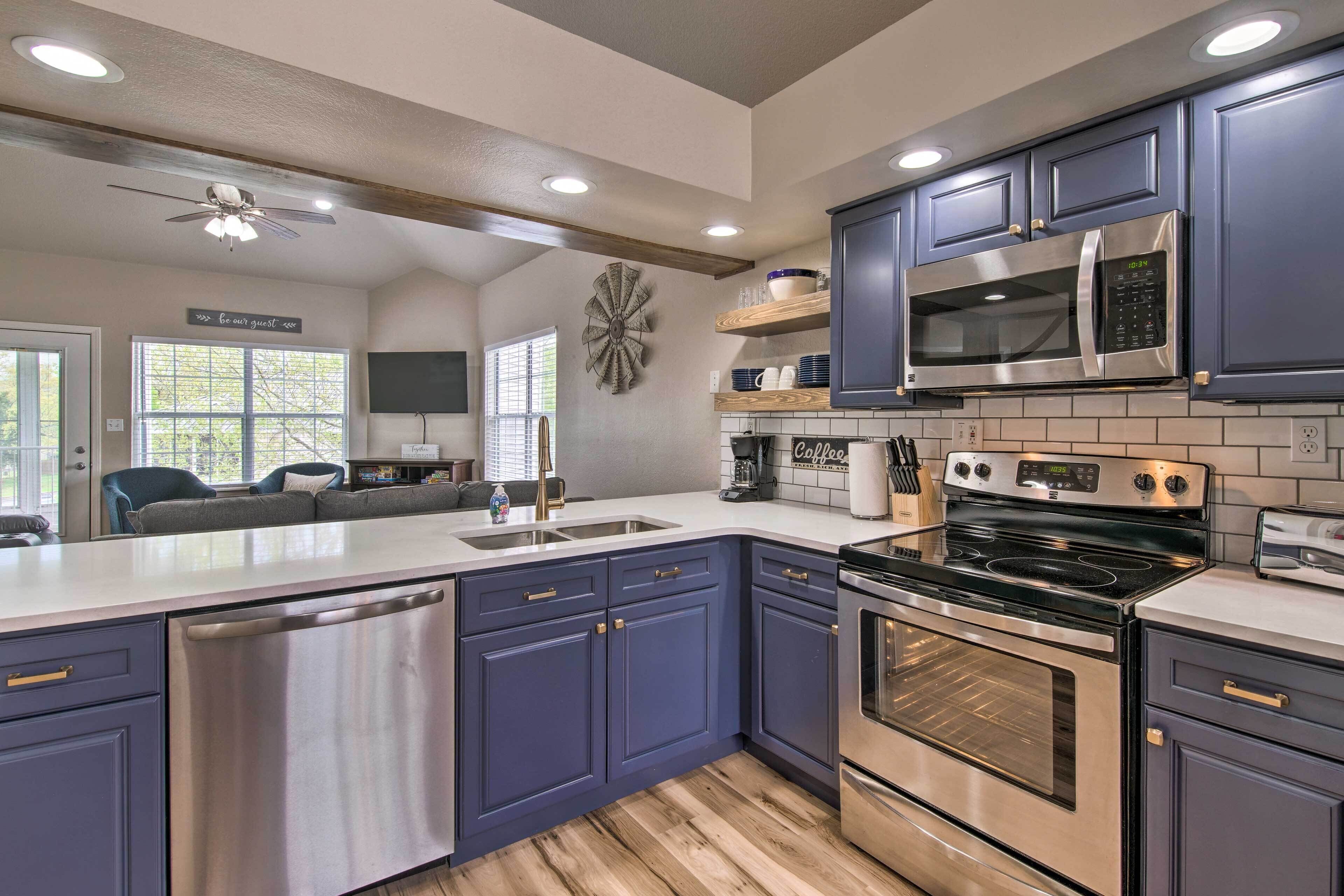 Una cucina moderna con mobili blu scuro, elettrodomestici in acciaio inossidabile e soffitto in legno.