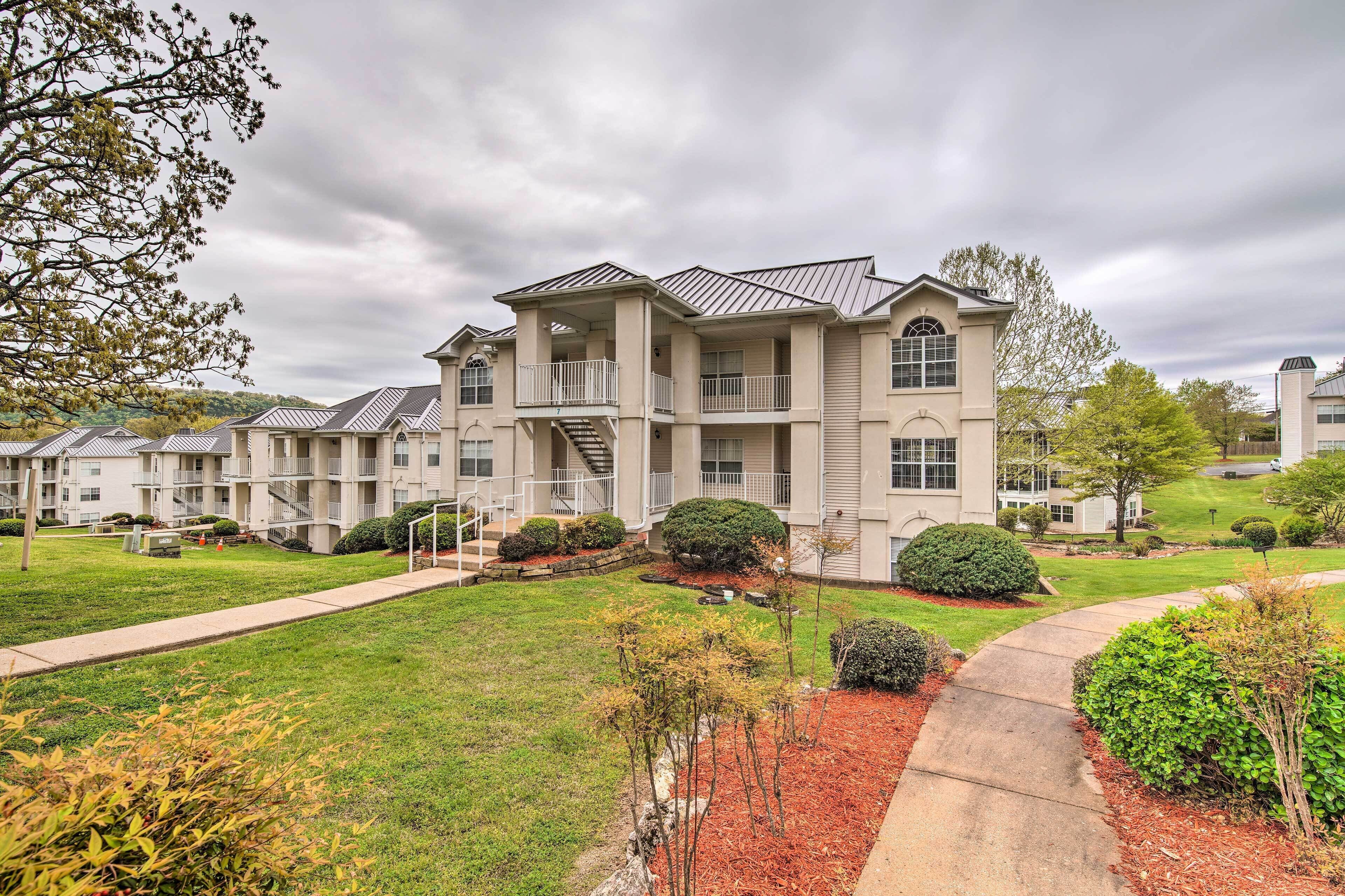 A multi-story residential building with a central courtyard, balconies, and a well-maintained lawn.
