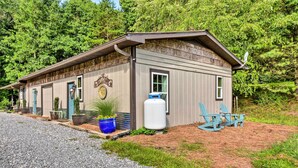 Un chalet rustique avec une allée en gravier, une grande citerne d’eau et un espace salon extérieur.