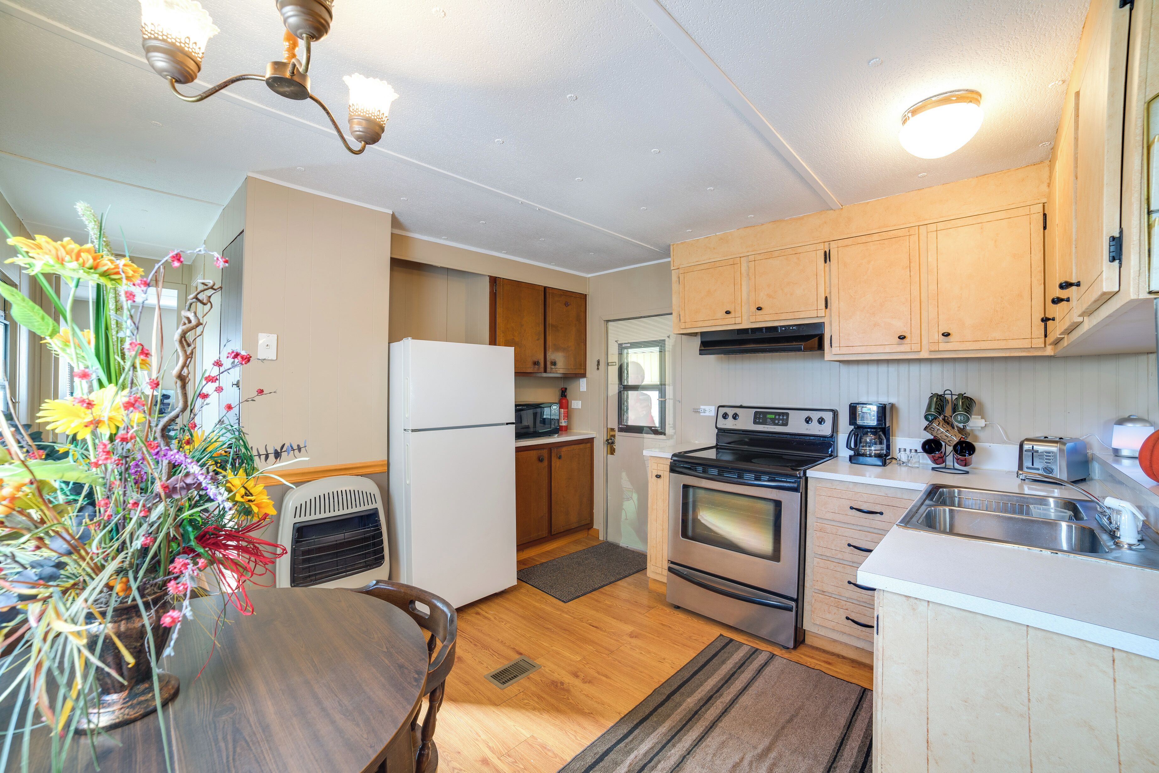 A compact kitchen with wooden cabinets, a refrigerator, stove, microwave, and a sink.