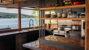 Una cocina moderna con vistas a un lago, equipada con electrodomésticos de acero inoxidable y estantes de madera.