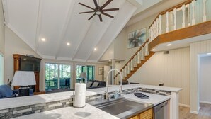 Une cuisine spacieuse dotée d’un grand îlot central, d’un lave-vaisselle encastré et d’un escalier en bois menant à l’étage supérieur.