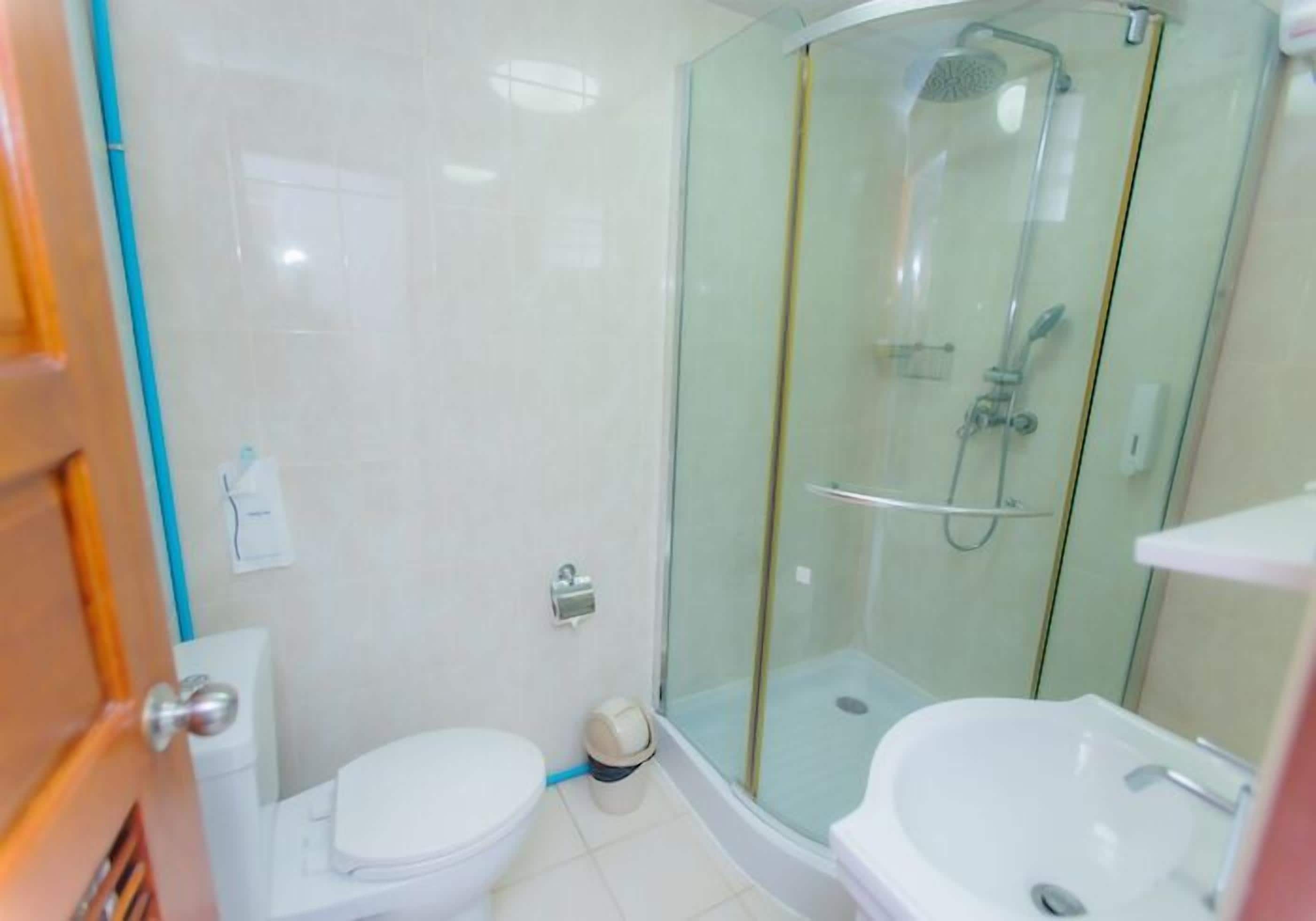 Une salle de bain avec une douche à parois de verre, des toilettes blanches et un lavabo.