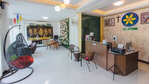 Zona de recepción con escritorio, sillas, sillón colgante y pared con logotipo e imágenes.