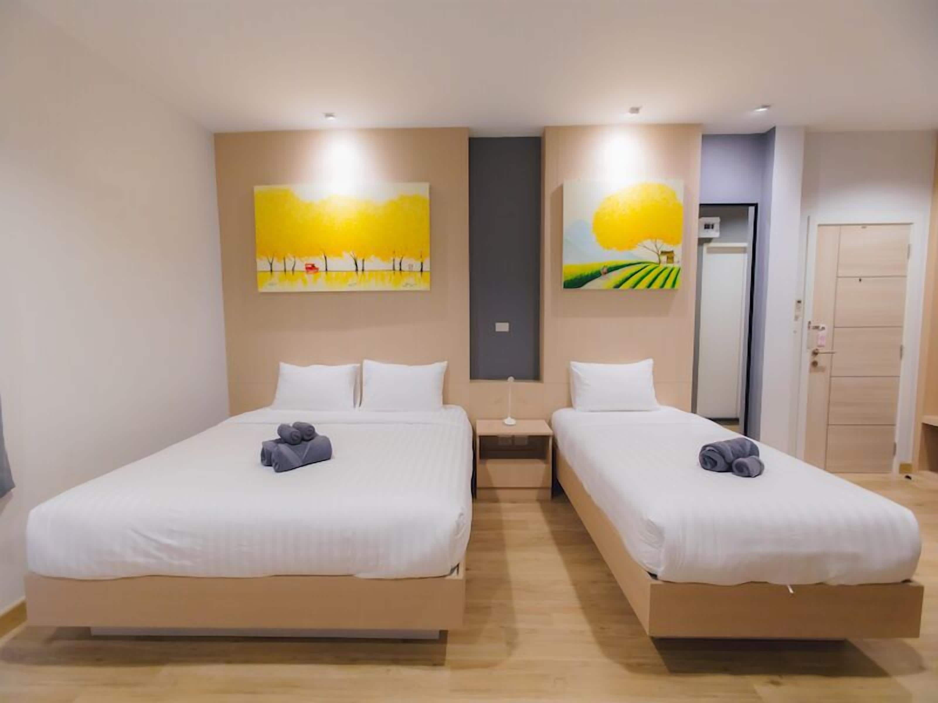 Una camera d'albergo con due letti, un comodino e opere d'arte alle pareti.
