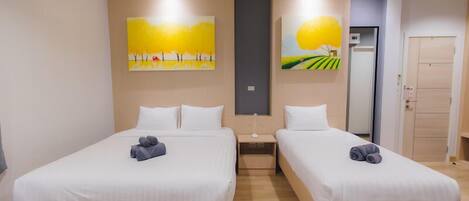 Una camera d'albergo con due letti, un comodino e opere d'arte alle pareti.