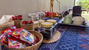 Una mesa con cestas que contienen aperitivos, tarros de conservas y una bandeja con tetera y tazas.