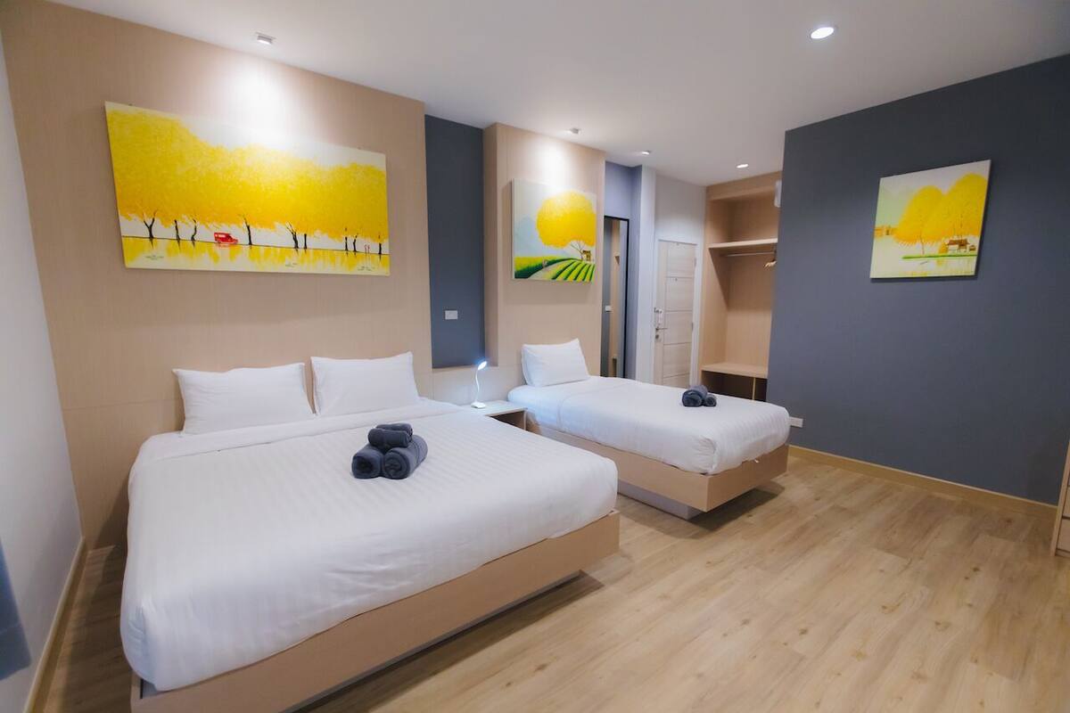 A hotel room with two beds, a wardrobe, and artwork on the walls.