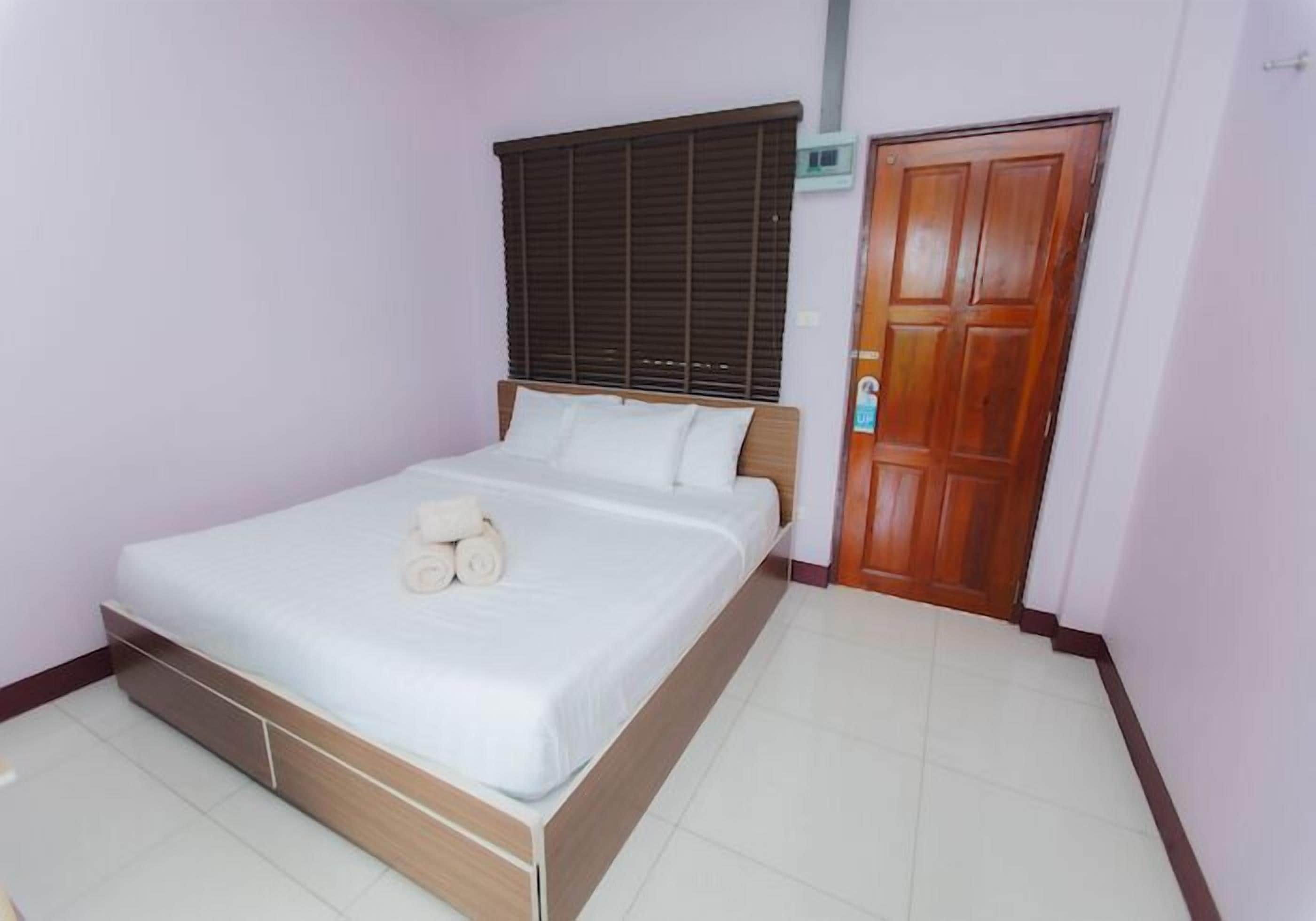 Un dormitorio con una cama, una puerta de madera y una ventana con persianas.