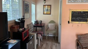 Une pièce confortable avec une kitchenette, un coin repas et un tableau noir sur lequel est écrit un message de bienvenue.