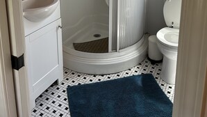 Une salle de bain avec un lavabo blanc, des toilettes et une douche dotée d’une porte en verre.