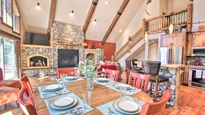 A dining area with a stone fireplace, wooden beams, and a kitchen with modern appliances. - 5 Mi to Crescent Lake: Dog-friendly Oregon Getaway (Crescent)