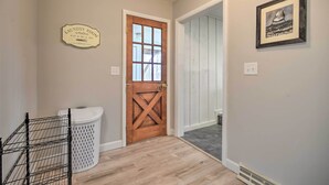A laundry room with a wooden door, a white laundry basket, and a framed picture on the wall. - Modern Studio < 13 Mi to Saratoga Racetrack! (Ballston Spa)