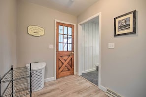 A laundry room with a wooden door, a white laundry basket, and a framed picture on the wall. - Modern Studio < 13 Mi to Saratoga Racetrack! (Ballston Spa)