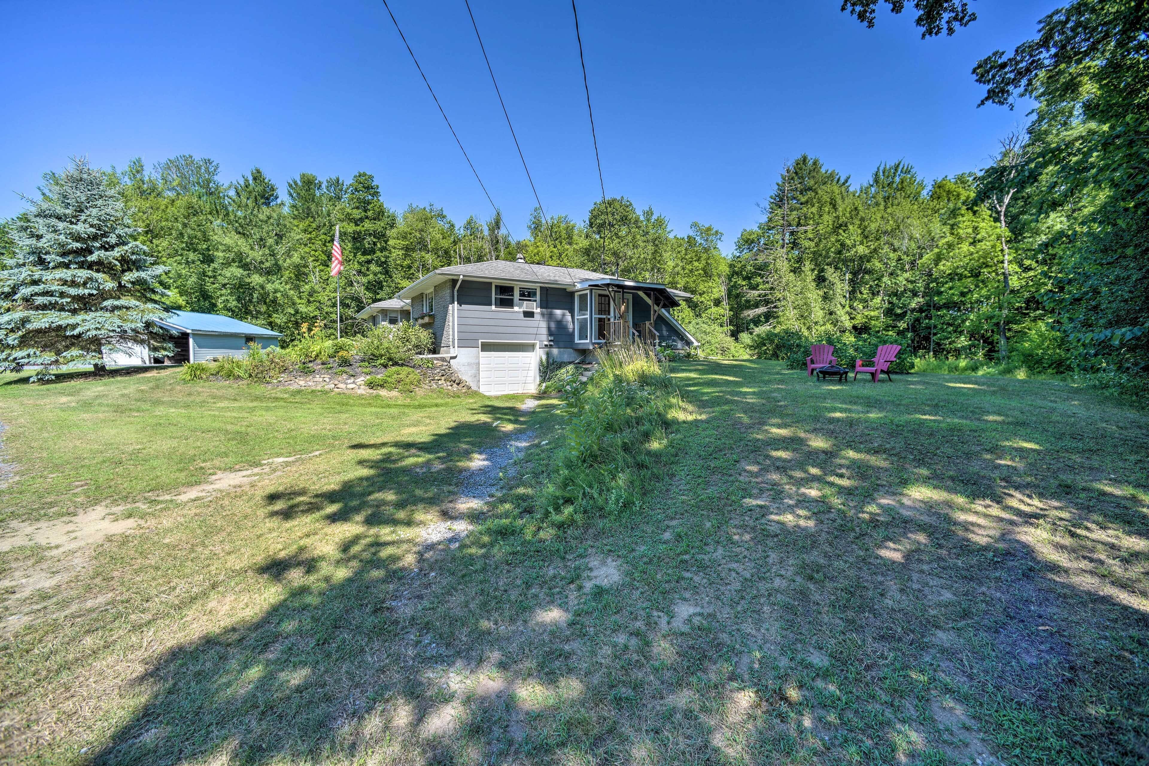 A house with a sloped roof, a front porch, and a yard with two pink Adirondack chairs.