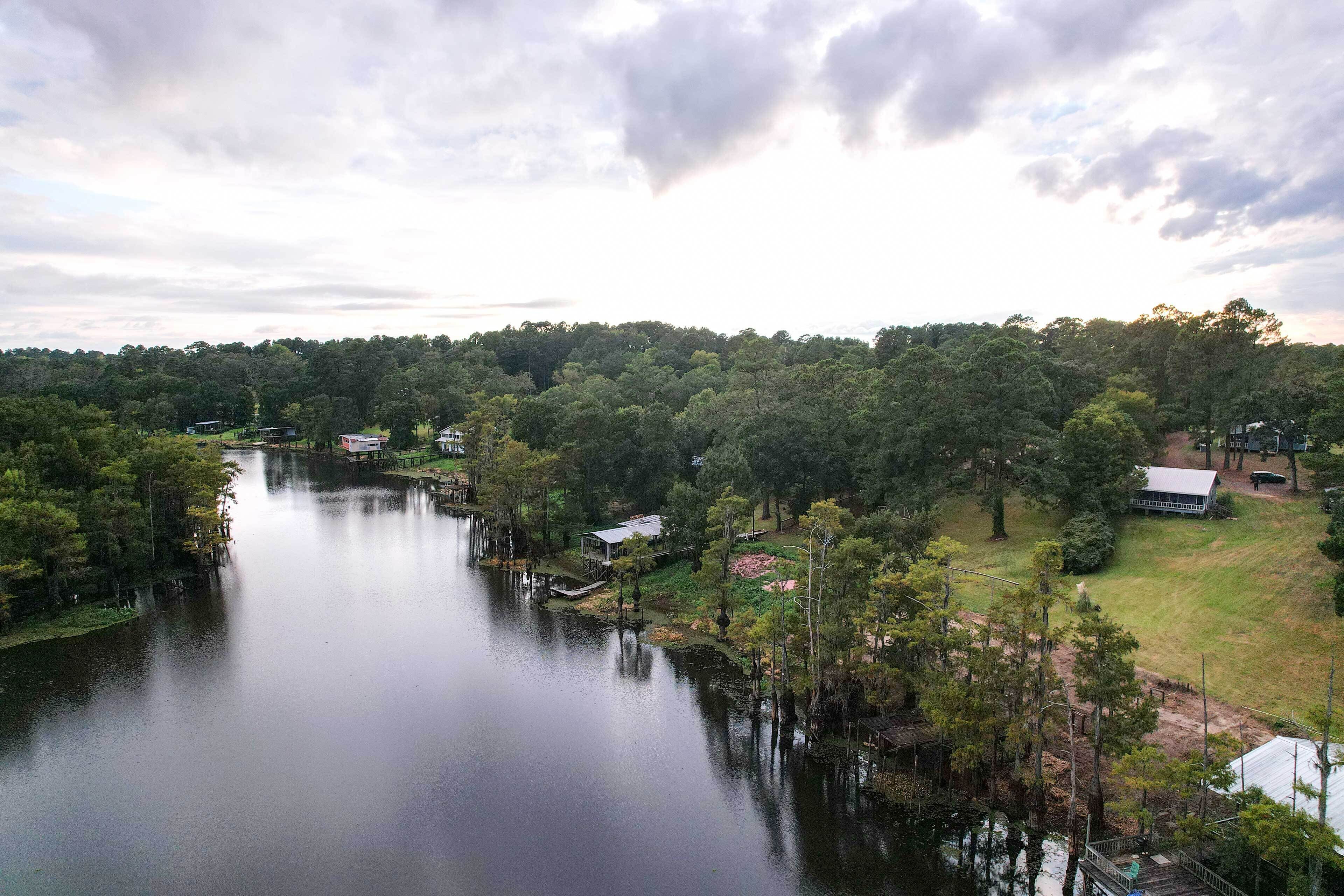 A river with houses along its banks, surrounded by trees.