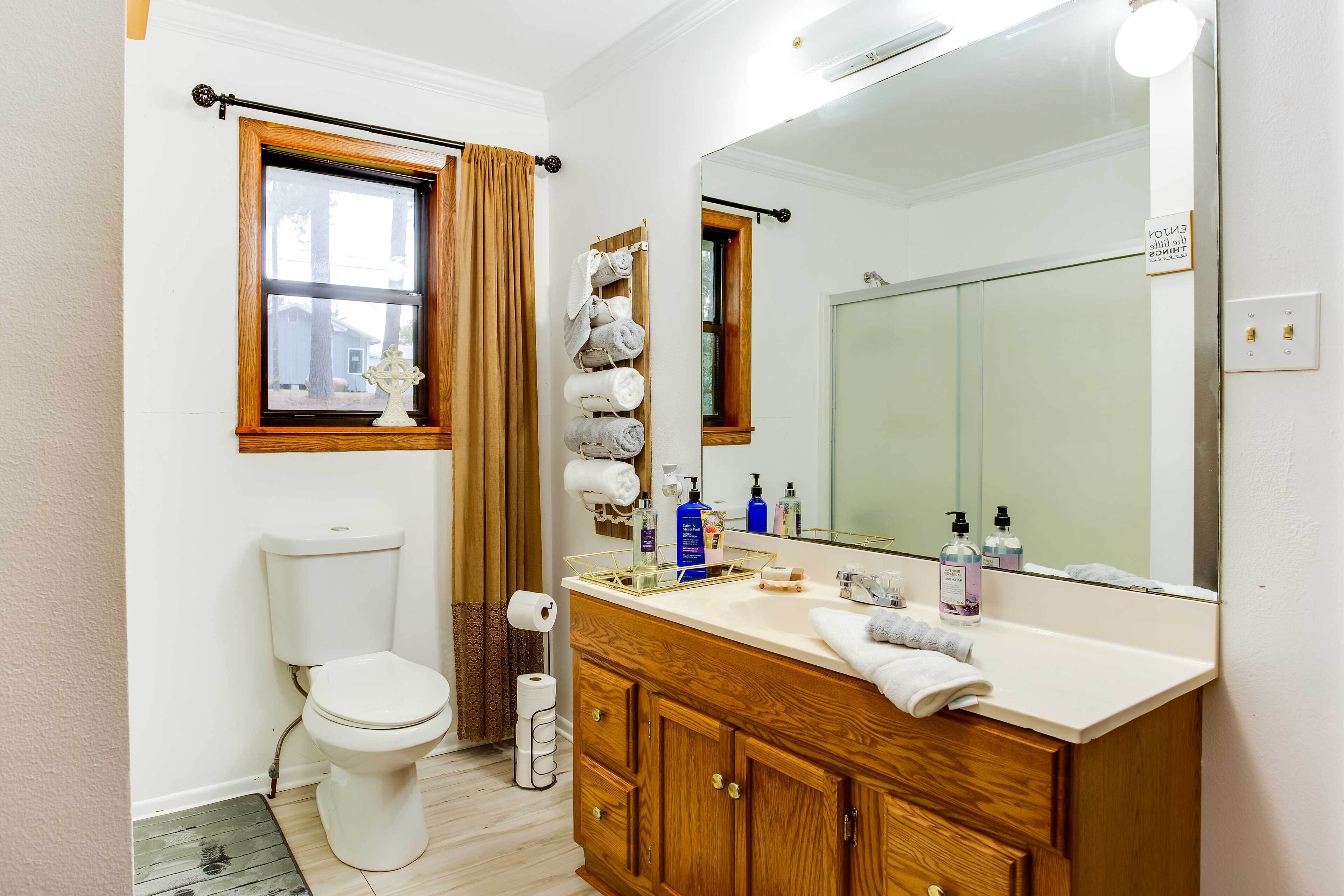 Une salle de bain avec des toilettes, un lavabo avec un miroir et des serviettes suspendues sur un porte-serviettes.
