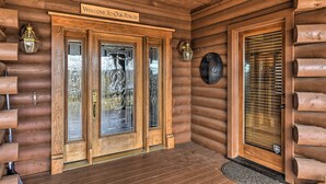 A wooden log cabin entrance with a welcome sign, a glass door, and a window with blinds. - Hot Tub, Grill: Hilltop Log Cabin in Hot Springs! (Hot Springs)