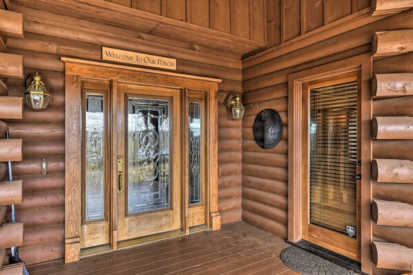 A wooden log cabin entrance with a welcome sign, a glass door, and a window with blinds. - Hot Tub, Grill: Hilltop Log Cabin in Hot Springs! (Hot Springs)